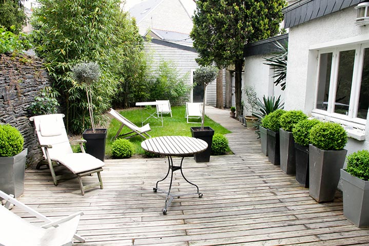 Une terrasse en bois nichée au coeur d’un jardin citadin.