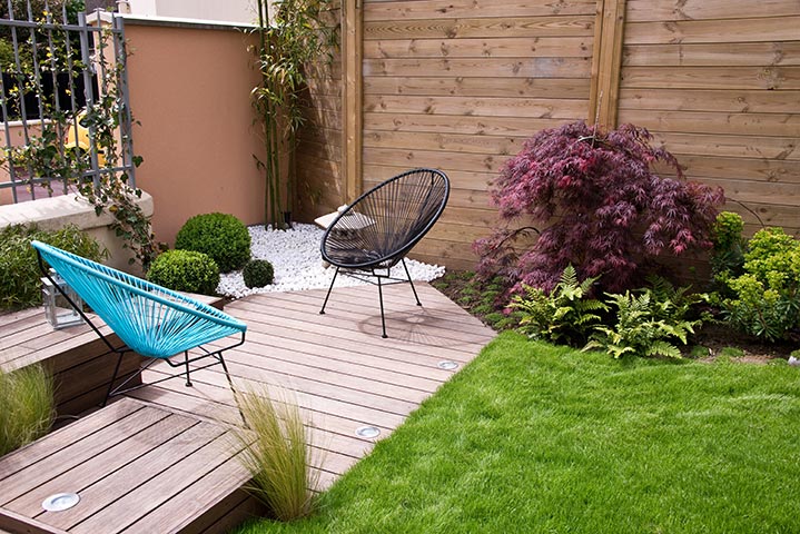 Un coin de jardin aménagée de deck et de verdure.