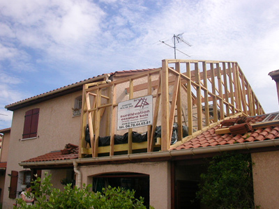 Une rehausse partielle en bois sur une maison maçonnée.