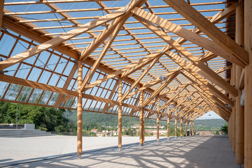 Photo d'un hall extérieur en structure bois utilisant des pieds en metal pour assurer la pérénité du bois.